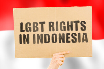 The phrase " LGBT rights in Indonesia " on a banner in men's hand with blurred Indonesian flag on the background. Equality. Human rights. Homosexuality. Love. Pride. Transexual