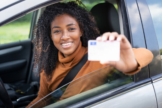 Young black woman at the wheel showing driving license