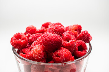 Frambuesas  frescas y congeladas con fondo blanco en vaso de cristal 
