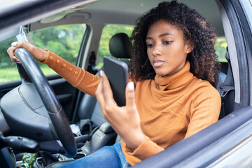 Fototapeta na wymiar Woman driving car distracted by her mobile phone