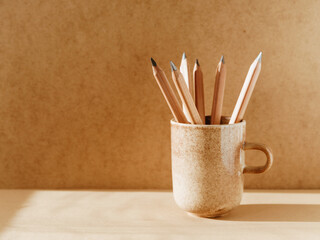Pencils in a ceramic mug on a table with copy space.