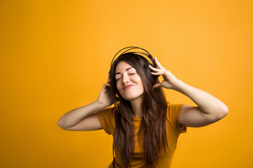 Portrait of laughing young woman listening to music and having fun in photo studio.