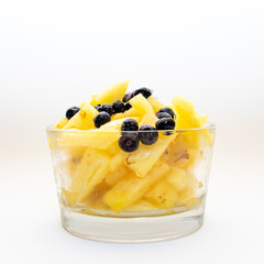 Piña con moras o arándanos azules  en vaso con fondo blanco