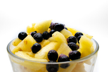 Piña con moras o arándanos azules  en vaso con fondo blanco