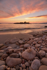 Reddish sunset on round stone beach on the beach called Santo do Mar, in Galicia.