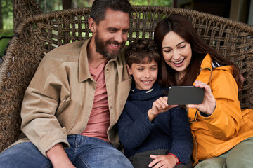 Happy loving family using modern smartphone outdoors