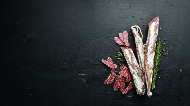 Spanish dry salami sausage Fuet with rosemary. Slice sausages. Rosemary. Top view. Free space for your text.