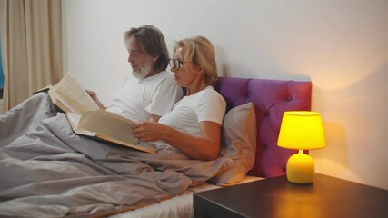 Senior couple relaxing and reading books in bed before sleeping - Powered by Adobe