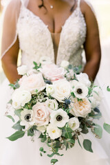 Black bride holding a beautiful wedding bouquet of flowers with white and pink roses and peonies. 