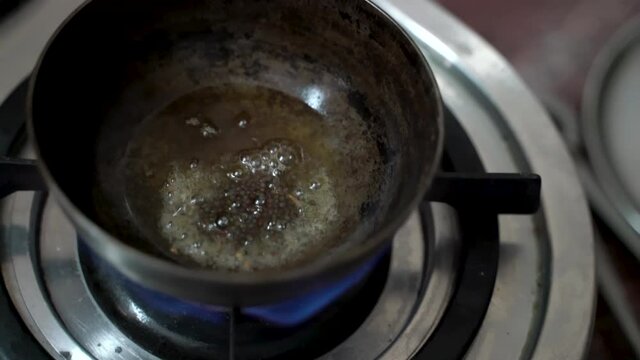 Black Peppercorn Put In A Small Deep Pan With Cooking Oil Over The Stove. - Close up-topdown Shot