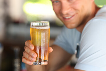 Smiling young man holding glass of beer. Harm of drinking alcoholic beverages concept.