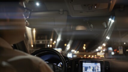 View from back seat of car at night, male driver in eyeglasses back. Night city shot, bokeh lights...