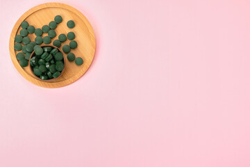 spirulina in tablets on pink background. Concept natural, eco, powder healthy dietary supplement. Copyspace