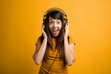 Portrait of laughing young woman listening to music and having fun in photo studio.