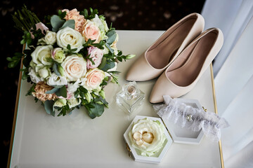 bridal accessories such as shoes, bouquet , ring and parfume on a table