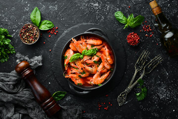 Food. Boiled shrimp in tomato sauce with basil on a black stone plate. Top view. Free space for your text.