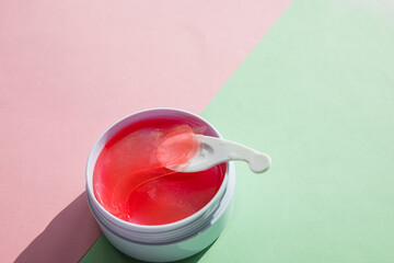 hydrogel cosmetic eye patch for skin care on pastel background. Product for face lifting, anti-aging wrinkles.Pink under eyes patches in a white container, anti aging skin care.copy space