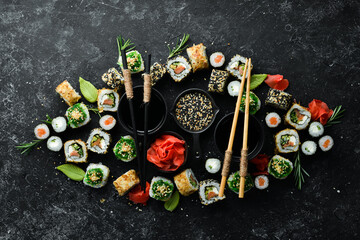 Set of tasty sushi and maki rolls on black stone background. Japanese food. Top view. Free space for your text