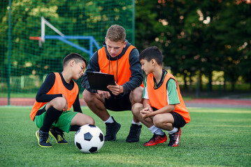Professional soccer coach tells the strategy of football game to his attentive teen players at...