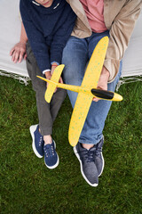 Father and son with toy plane sitting on hammock swing