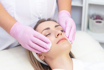 Fototapeta na wymiar cosmetology. Close up picture of lovely young woman with closed eyes receiving facial cleansing procedure in beauty salon.