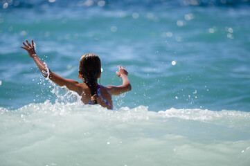 danger storm weather with little girl swimming in high waves in sea during summer vacation with copy space