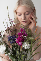 Charming young woman with closed eyes holding flowers