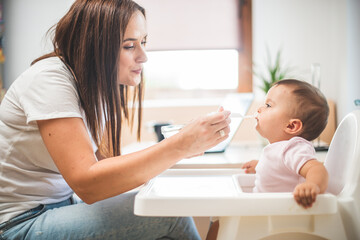 Mother feed her little daughter with a spoon