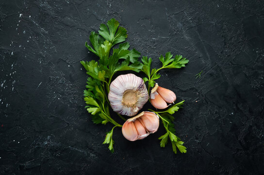 Fresh parsley and garlic on a dark background. Vegetables. Top view. Free space for your text.