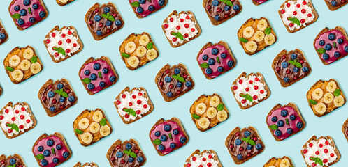 Pattern with set of different sweet sandwiches: with chocolate butter, peanut butter, soft cheese, berry curd, decorated with fruits and berries. Light blue background. Top view. Flat lay.