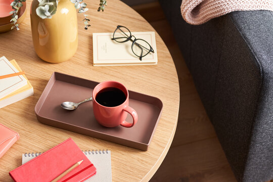 Cup of tea amidst notepads and vase on table