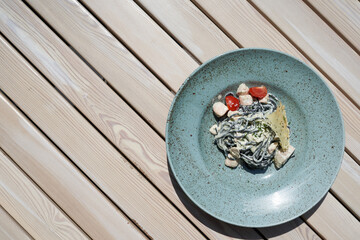 Large plate with a small portion of pasta with fish on a wooden table