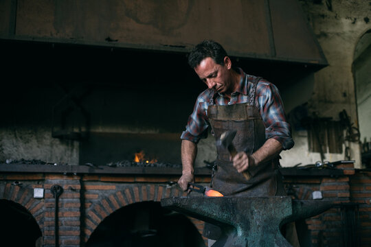 Blacksmith forging metal in workshop