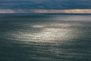 Storm clouds clearing over vast ocean at dusk