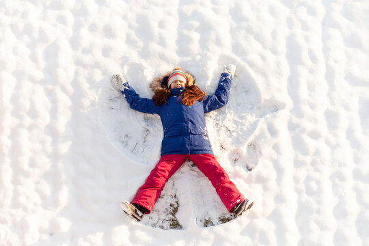 Happy elementary-age girl making a snow angel