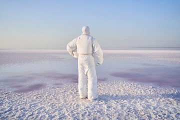 Astronaut standing with back on salty lake