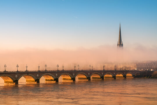 Basilique Saint-Michel sous la brume avec le Pont de Pierre au lever du soleil le long de la Garonne