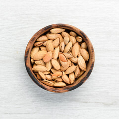 Almonds in bowl on white wooden table. Top view. Free space for your text.