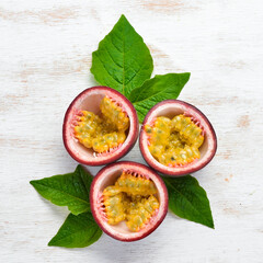 Passion fruits with a leaf on a white wooden background. Tropical Fruits. Top view. Free space for text.