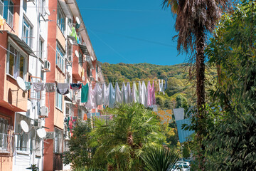 Fototapeta na wymiar Clothes are dried on the clothesline outside near the house with satellite dishes against the backdrop of palm trees and a tree-covered hill, washing clothes in the province