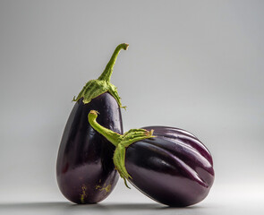 Two fresh round and oblong eggplants on a solid background.