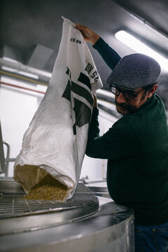 Brewer adding malt into tank