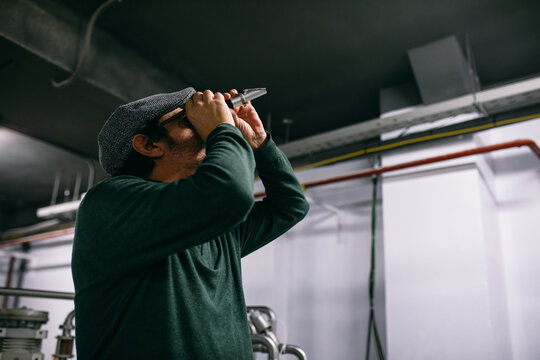 Brewer examining beer in refractometer