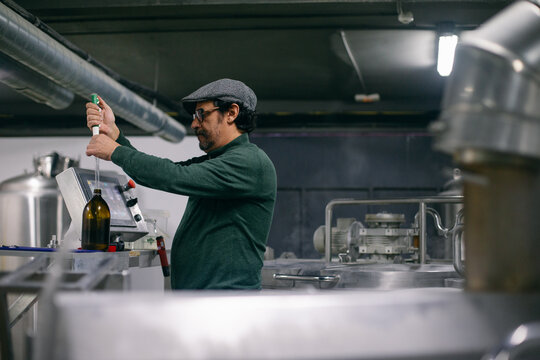 Adult Brewer Taking Flavor Extract From Bottle