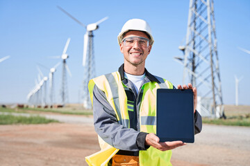Manual worker holding tablet on windmills background