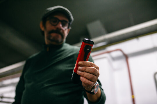 Male brewer using manual hydrometer