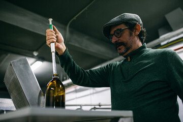 Adult brewer taking flavor extract from bottle