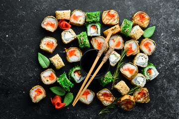 Big set of sushi rolls with seafood on a black stone background. Top view. Free space for your text.