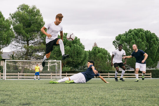 Soccer player avoids incoming slide tackle during a soccer match - Powered by Adobe