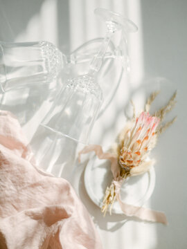 Dried Protea and crystal champagne glasses in light
